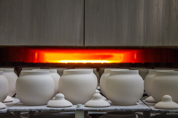 New ceramic identical white pots sent to a muffle kiln for firing at a porcelain factory in the...