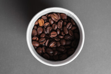 Coffee in a paper cup on the table. Coffee beans in a disposable paper cup on the table. Grains of coffee near a paper cup of coffee