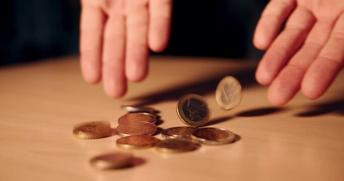 Hand drops some European coins on the table. Man's hands lay a pile of 50 cents, one and two euro coins. Wealth, investment and money. Close up of hands full of money. Slow motion video in 4k.
