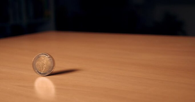 2 euro spinning top coin. Two euro coin spinning around on a table. Wealth, investment and money. Close up of a single coin that stops spinning in focus. Slow motion video in 4k.