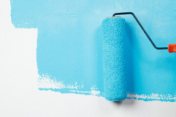 Roller Brush. Painting on surface wall apartment, renovating with blue pastel color. Leave empty copy space white to write descriptive text beside.