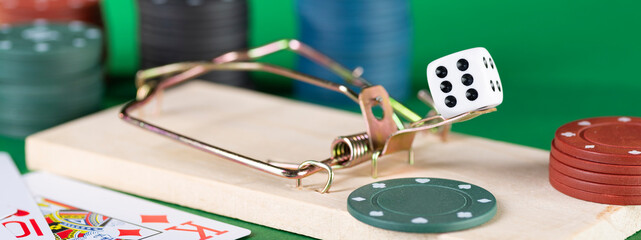 Dice and mousetrap, game trap, on a green background, get into gambling addiction
