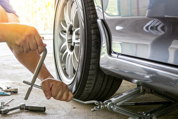 Home service car concept : A man repairing action remove bolt of car wheel for check the car's...