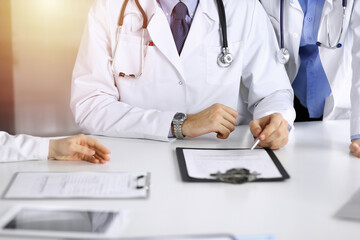 Group of unknown doctors are sitting at the desk and discussing problems or disease treatment in...