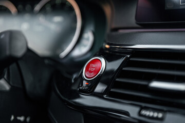Plakat Sports car dashboard with focus on red engine start stop button. Button engine start and engine stop. Car inside. Ignition remote starter. Modern car interior details. Selective focus.