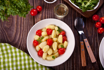 Homemade Italian gnocchi with tomato cherry on the wooden table