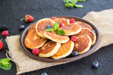 A healthy breakfast of cheese pancakes, berries, and honey. Creative atmospheric decoration