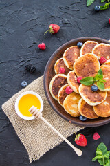 A healthy breakfast of cheese pancakes, berries, and honey. Creative atmospheric decoration