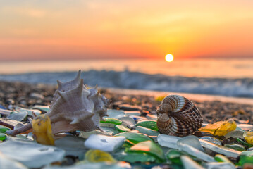 Beautiful sandy beach with sea glass, shells and pebbles sparkling under the warm sun at sunset with waves and calm sea, suitable for PC, tablet and laptop wallpapers, beautiful beach and sea, summer.