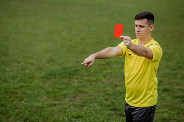 Angry football referee showing a red card and pointing with his hand on penalty
