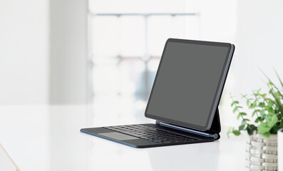 Computer tablet with blank screen on white table in modern office room.