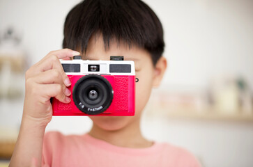 Little asian boy taking a picture with a retro camera : close up