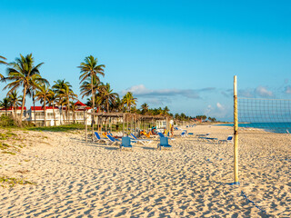 Cayo Coco, Cuba, 16 may 2021: Sandy beach of the hotel Tryp Cayo Coco with sun loungers and tall palm trees. People relax and sunbathe near the ocean on sun loungers.