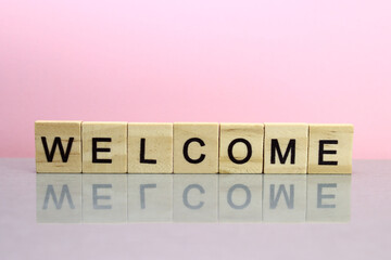 Welcome word made of wooden letters on a pink background