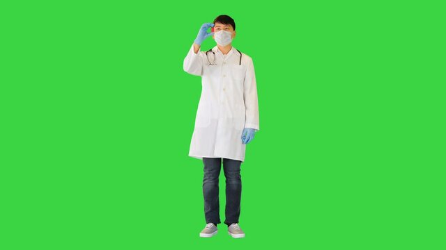 Young asian doctor is showing two ampules with red and blue solution on a Green Screen, Chroma Key.