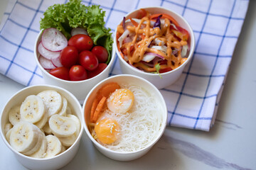 Take away healthy food in foil boxes on marble table.