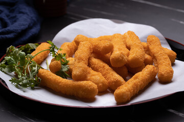 Chicken nuggets sticks in a cup on black background.