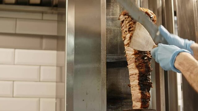 Arabic fast food shawarma. A cook cuts meat to make shawarma, gyros 