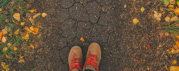 banner with casual unisex boots with bright laces and colorful autumn fallen leaves. Autumn fall scene. Conceptual image of legs in boots on dry earth and autumn leaves. Lifestyle Top view. 