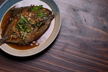 Crispy fried pomfret with sweet sauce. Thai food on wooden background.