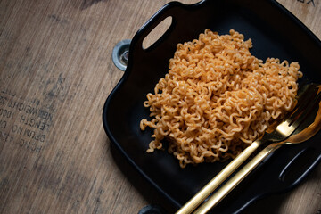 Korean instant noodles in a black plate and a golden spoon