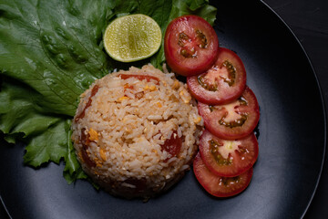 Red salted egg fried rice with vegetables in black plate