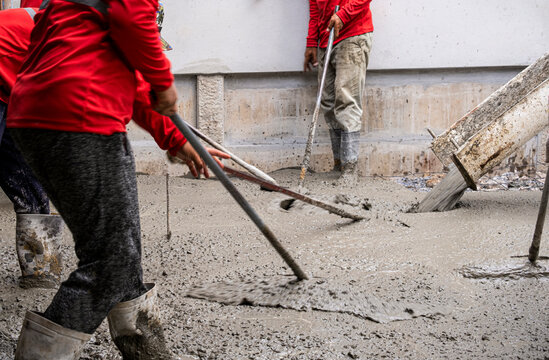 three worker team working wet cement  on floor by use trowel with long Tools spreading poured concrete for strong street after dry.