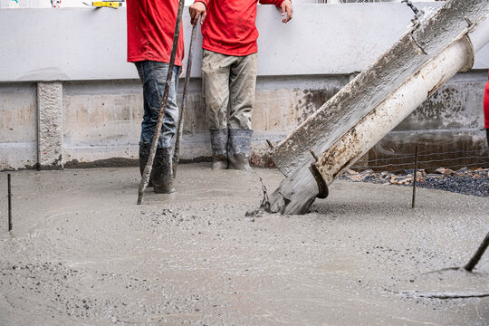 two worker team working wet cement  on floor by use trowel with long Tools spreading poured concrete for strong street after dry.