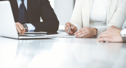 Business people discussing contract working together at meeting in modern office. Unknown businessman and woman with colleagues or lawyers at negotiation