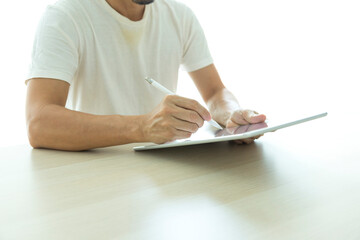 Obraz premium Young man using tablet with blank screen on table at coffee shop or home office.