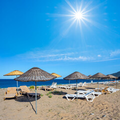 sandy sea beach with sun umbrella at the sunset, evening summer vacation background