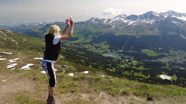 Girl jumping in SLOW MOTION on Piz Scalottas top of Switzerland. Tourist resort for ski activities in winter and bike in summertime.