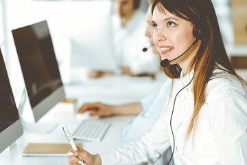 Group of diverse operators at work in call center. Beautiful asian woman sitting in headset at customer service office. Business concept