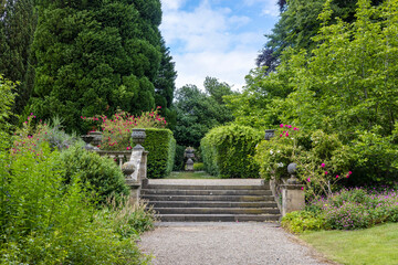 Old stone terraced garden steps and balustrade with decorative planters in a park.