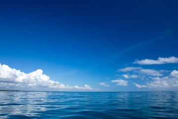 clouds on blue sky over calm sea with sunlight reflection