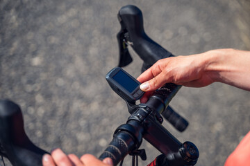 Close-up of a woman cyclist's hands turning on her bike's Gps Navigator to start a burp in the...