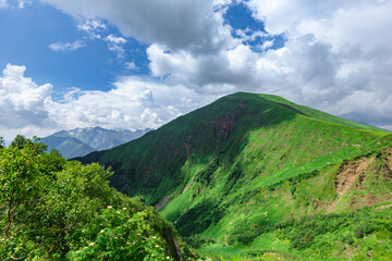 Fototapeta premium Green mountain peak. Layers of mountains in the haze during sunset. Krasnaya Polyana, Sochi, Russia.