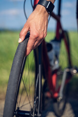 Fototapeta na wymiar Vertical close up of a woman cyclist's hands checking the bike wheel tire pressure, before starting her bike route outdoor.
