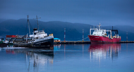 Old black ship and new red ship anchored in Beagle Channel waters in Ushuaia, Tierra del Fuego,...