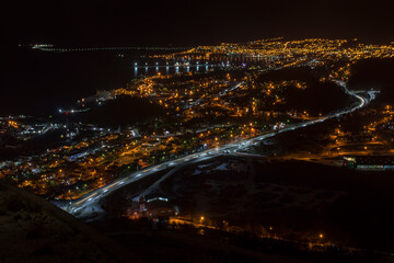 Fototapeta na wymiar Panoramic night view of Ushuaia city, Tierra del Fuego, Argentina. Lights on the pu-left corner are from the road to the airport.