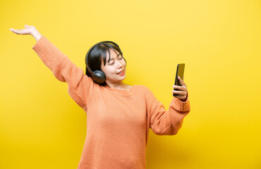 oung girl with headphones on yellow background
