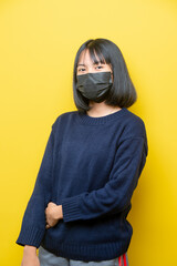 Studio portrait of young  girl  wearing medical face mask against coronavirus. Background of yellow color.