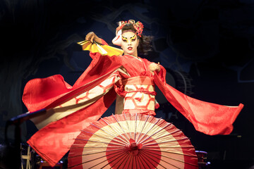 Woman dances with a fan and umbrella, with flowing sleeves. Traditional Japanese performance red...