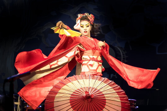 Woman dances with a fan and umbrella, with flowing sleeves. Traditional Japanese performance red fox dance. Kino Kitsune fox is a character in Japanese legends.