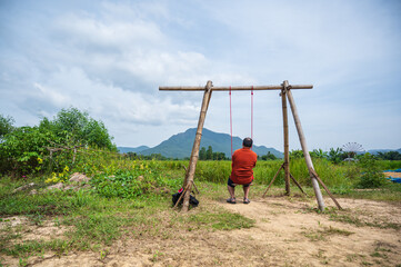 Asian fat guy sitting on wooden swing with Beautiful landscape view at loei thailand.