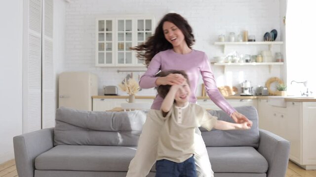 Funny active family of single female parent and hyperactive preschooler son have fun at home on lockdown. Happy mother and cute kid dancing, moving to favorite pop song relax together in living room