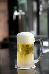 delicious mug of super cold and refreshing draft beer on the table in the blurred background