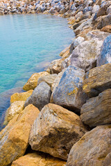 Fototapeta na wymiar Sea storm protection dam with stone blocks against the sea water