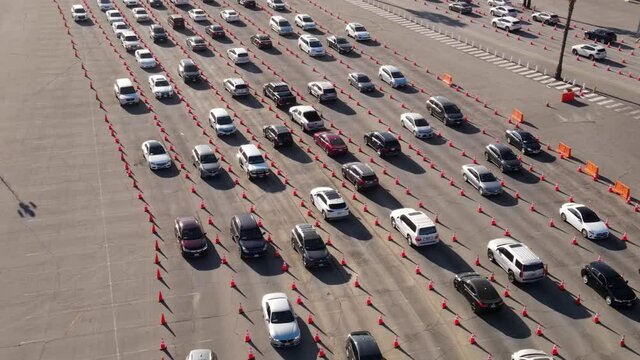 Aerial shot of 1000’s of people in cars waiting in line at a drive-through testing site to be tested for Coronavirus or to receive the vaccine.