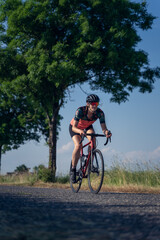 Vertical, Angle photo of a young woman, pedaling, riding speed a road bike, on a ride through nature. Gender equality in sport Concept.
